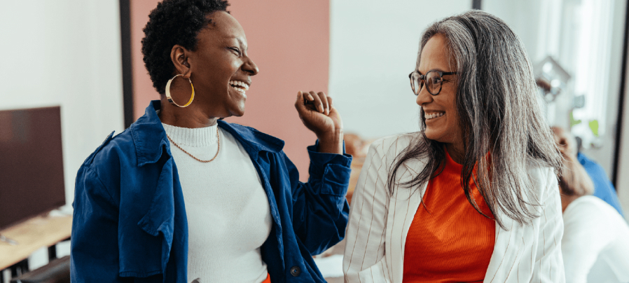 Two women in a professional setting talking and laughing.